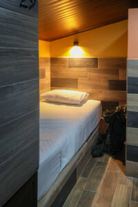 Private capsule-style dorm bed with reading light and charging ports in Cayala mixed dorm
