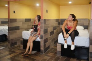 Guests relaxing beside capsule beds in Cayala mixed dorm with shared bathrooms
