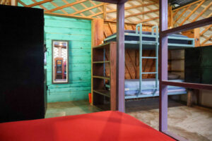 Rustic mixed dorm bunk beds with lockers and shared fan in the Noisy Dorm