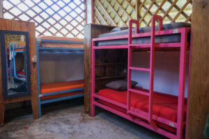 Colorful bunk beds with privacy partitions in the Noisy Dorm at Greengo’s Hotel