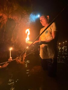 Guide leading candlelit cave exploration through underground waters in K’anba Cave