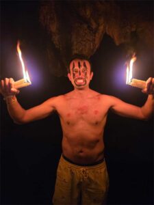 Traveler with candle inside dark underground cave during K’anba Cave Tour