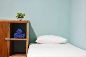 Minimalist single bed setup in El Barrio semi-private room with wooden storage