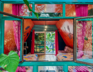 Double queen loft room with vibrant jungle-inspired decor and balcony access